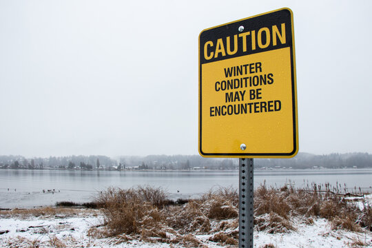 View of sign Winter Condition may be Encountered with snow in the background. Courtenay riverway trail.