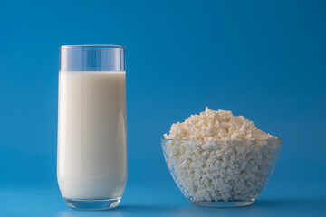 White milk in a glass and cottage cheese on a blue background. Dairy product concept