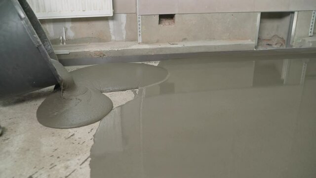 Contract painter painting garage floor to speed up selling of home. Floor leveling. Filling the floor with a self-leveling compound. Self-leveling floor. floor repair, liquid mixture, leveling