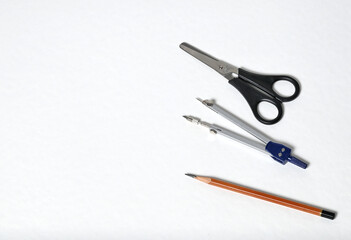 Compass, scissors and pencil on a white background. Top view.