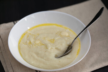 Semolina porridge or wheat cream in white plate with milk and butter. Breakfast is ready