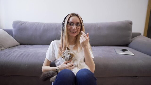 Webcam view woman in headphones hugs cat shoots video for blog with pet