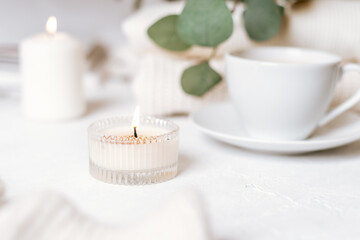 Details of still life in the home interior of living room. Cup of coffee, cotton, book, candle, sweater. Moody. Cosy autumn winter concept on white background. Decoration.