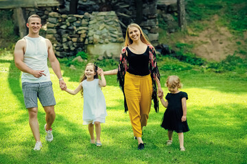 Fototapeta premium Happy family on summer landscape. Freedom, activity, lifestyle, energy concept. Childhood. Mothers and fathers day. Children and parents walk on green grass.