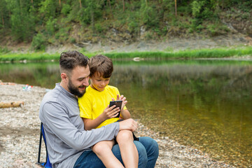 Young man and boy watching something on smart phone and enjoying in outdoor
