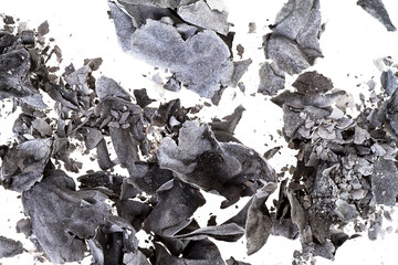 Pieces of burnt paper on a white background. The ashes of the paper as background.