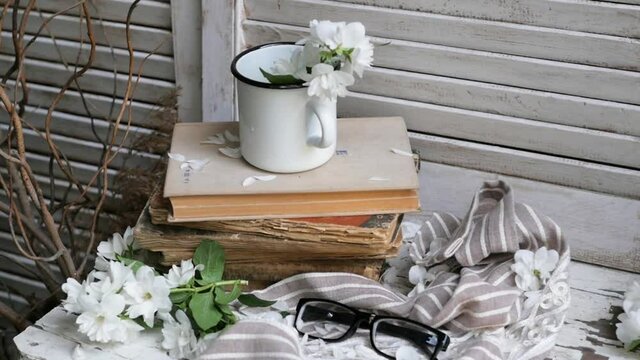 Still life with an old book, a metal mug and white flowers. composition in a rustic style.