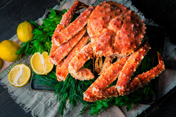 Tasty king kamchatka crab with lemon slices on wood board