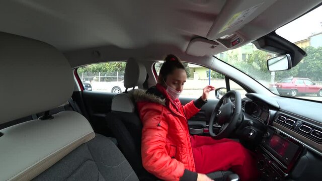 Fethiye, Turkey - 18th of February 2021: 4K Woman in car puts on her mask and backs out
