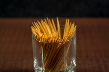 Toothpicks in a glass on a brown wooden table, photo for design