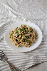 Homemade Chicken Alfredo Penne with Parsley on a white plate, low angle view. Copy space.