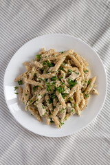 Homemade Chicken Alfredo Penne with Parsley on a white plate, top view. Overhead, from above, flat lay.