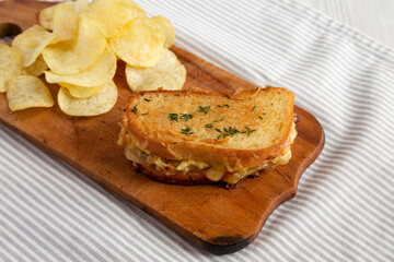 Homemade French Onion Melt Cheese Sandwich with Chips on a rustic wooden board, side view.
