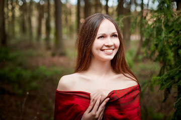 Beautiful young brunette woman with long hair in a forest pines and firs on a summer day