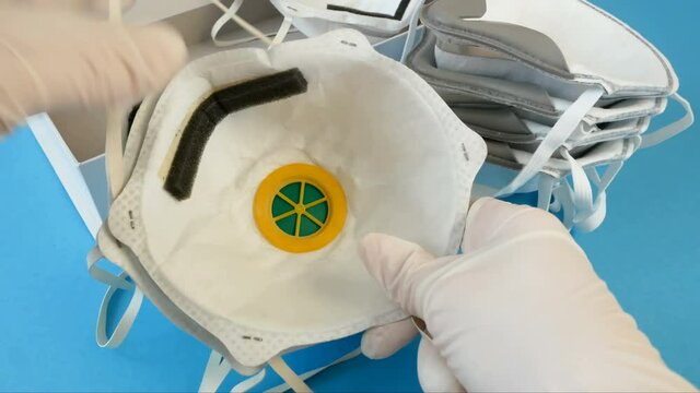 Hand in medical gloves packing many different respirators with high protection level 3M. Protection against coronavirus. Respritors production, packing and delivery