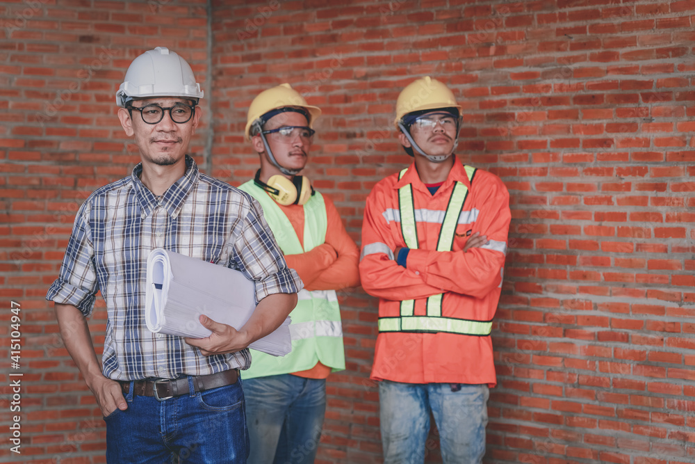 Poster workers with blueprint works on the construction site.