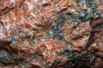 Background with the surface of a piece of red granite interspersed with quartz in soft focus under high magnification