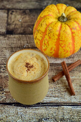 Pumpkin spice latte in a glass with cinnamon. Wooden background
