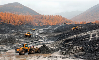 Wheel loaders and bulldozers in operation in an industrial mountainous area