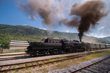Old steam train leaving the railway station of Tolmin, Slovenia stone bridge