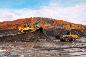 Wheel loaders and bulldozers in operation in an industrial mountainous area