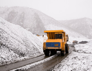 A mining dump truck in an industrial mountainous area in the process. Mining
