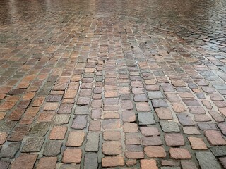 Wet cobble stone pavement made of square granite blocks on a rainy day, very clean