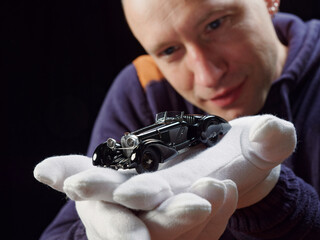 GOMEL, BELARUS - February 16, 2021: portrait of a collector of retro car models on a black background