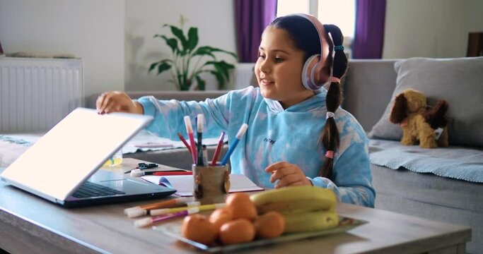 Cute little girl greets the teacher at the end of the online lecture at home. Child girl doing school homework with woman teacher, using laptop computer at home, learning in virtual school on laptop 