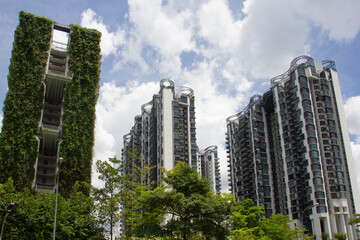 View at tall buildings or condo at Singapore in green grass and leaves, trees and at blue sky with clouds, eco life with fresh air at modern city of the future.