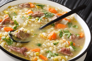 Tasty Scotch Rich broth filled with bite-sized pieces of root vegetable and tender lamb closeup in the plate on the table. Horizontal