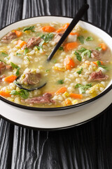 Traditionally Scotch Broth is made with lamb cooked with the vegetables, barley, and dried peas closeup in the plate on the table. Vertical