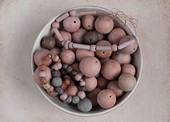 Handmade clay beads, necklace and bracelets. Ceramic handcrafted items in a stoneware plate. Top view.