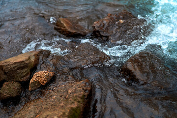 Stones in the rough river water. Stones under water. View from above. Winter fast river.