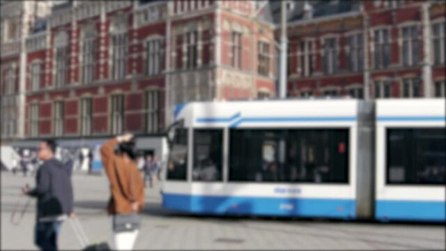 Modern tram moving through the public area outside Amsterdam Central Railway Station.