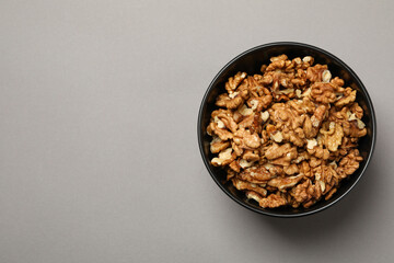 Bowl with tasty walnuts on gray background