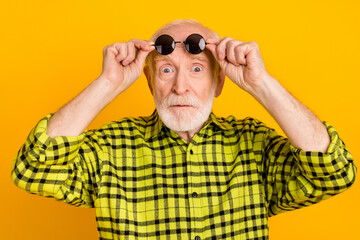 Photo of aged man amazed shocked surprised fake novelty news hands touch glasses isolated over yellow color background