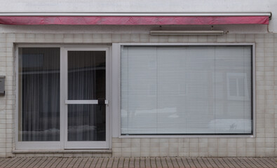 entrance of a little shop with closed blind at the window during corona pandemic