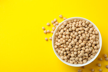Bowl with fresh chickpea on yellow background