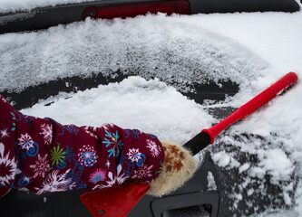 Hand of woman using brush and remove snow and ice from car and windscreen, concept of...