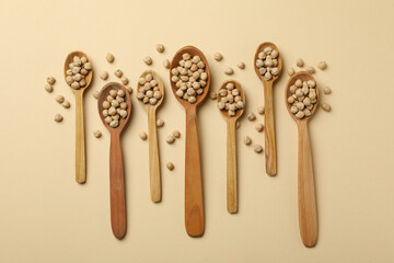 Wooden spoons with chickpea on beige background
