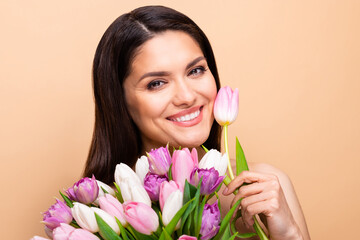 Photo of cheerful attractive young woman hold flowers clean skin face isolated on pastel beige color background