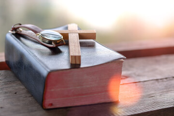 Close up the Cross on the holy Bible with a wrist watch in morning, christian concept.