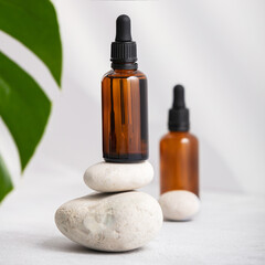 Bottles of dark amber glass with essential oil and tropical leaf