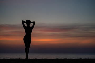 Silhouette portrait of woman wearing bikini on the beach, golden sunset moment. Holiday and travelling concept.