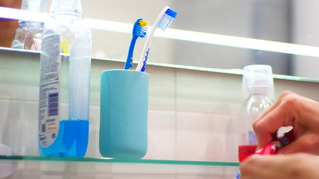 Women in the bathroom puts toothpaste on the toothbrush  and brushes her teeth