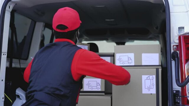 African delivery man loading boxes in the truck while wearing face mask to avoid corona virus spread - People working with fast deliver during corona virus outbreak