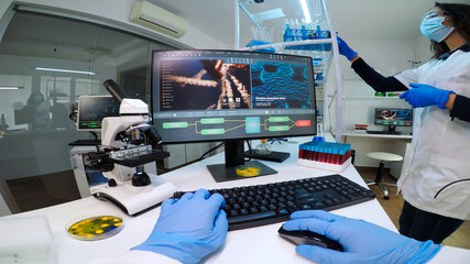 POV of man biologist checking DNA information typing on pc in modern equipped laboratory. Scientists examining vaccine evolution in medical lab using high tech, chemistry tools for scientific research