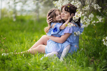 Fototapeta premium happy mom and daughter are walking in the blooming garden