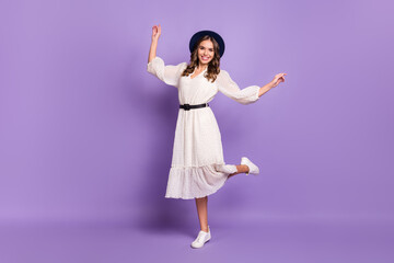Full length body size photo of smiling in dotted dress woman holding black hat isolated on bright violet color background